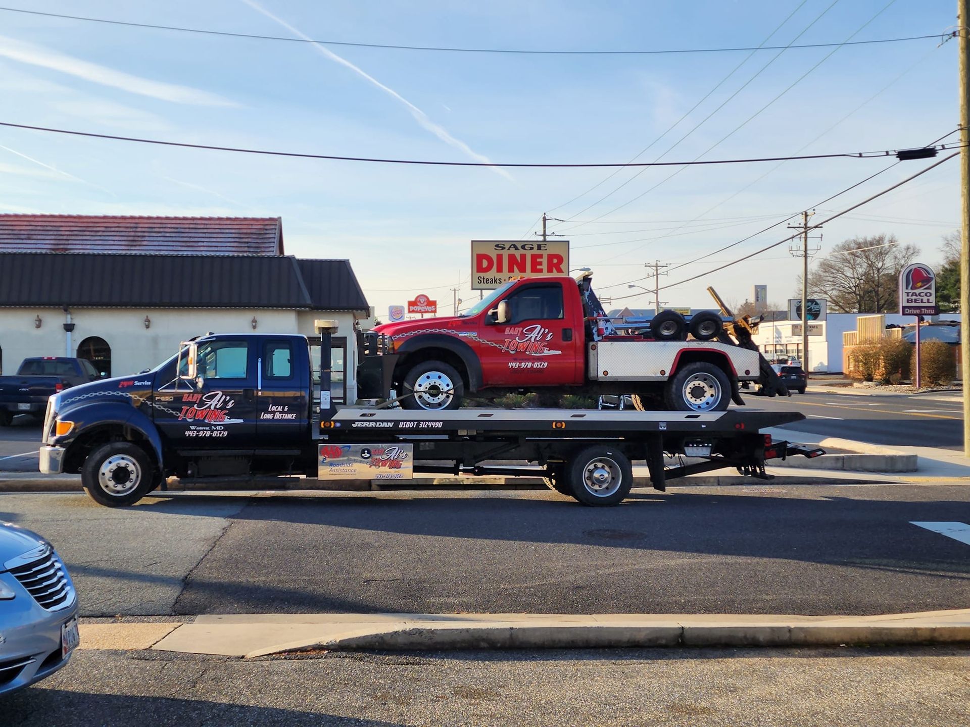 a tow truck is carrying a red truck and a white car .