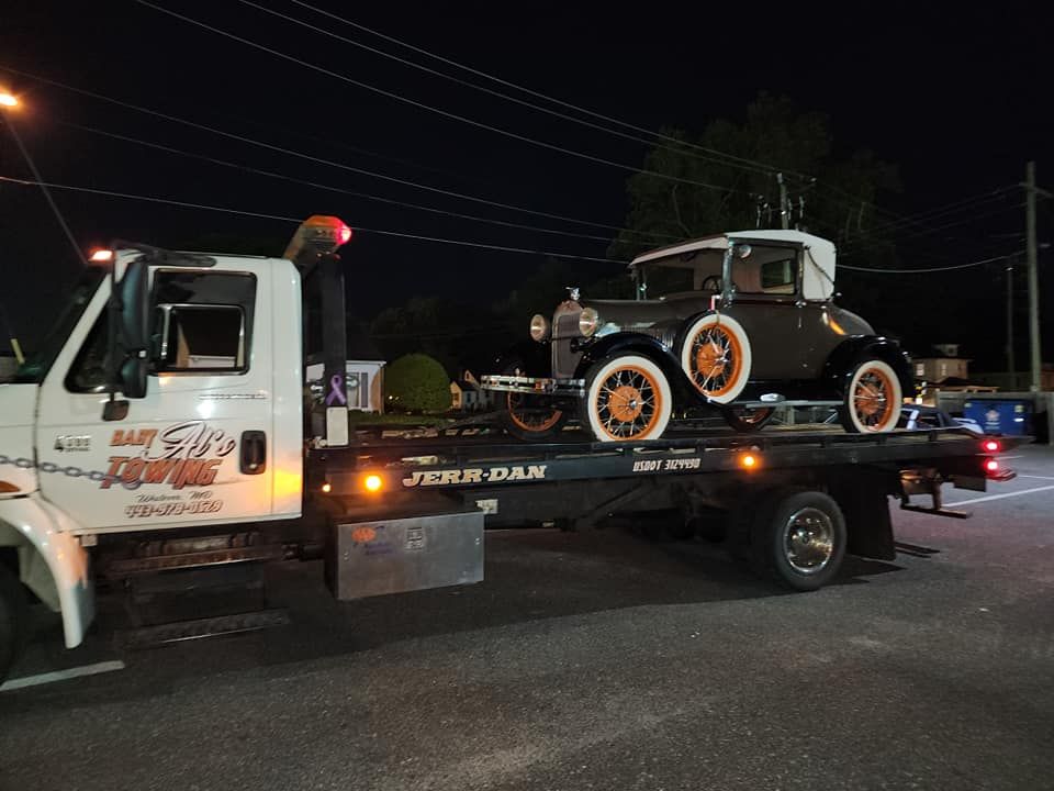 an old car is being towed by a tow truck .