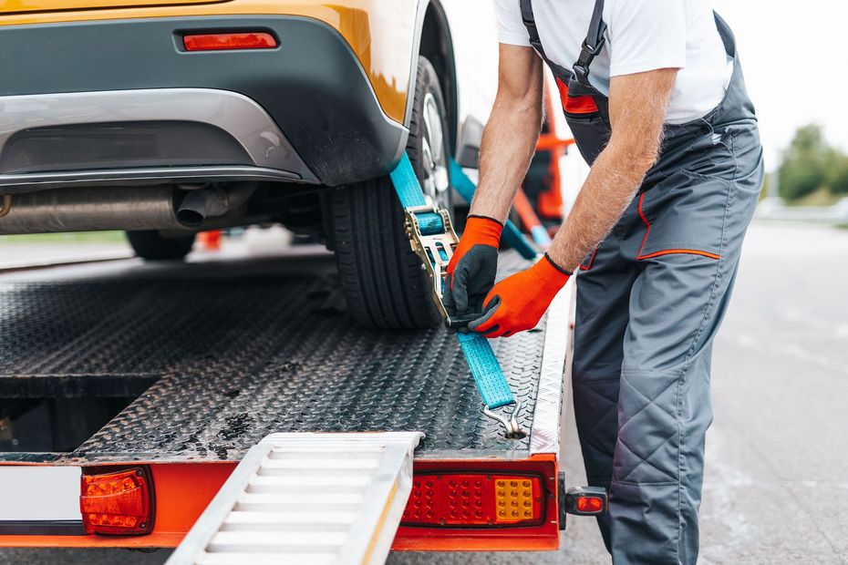 a man is tying a car to a tow truck .