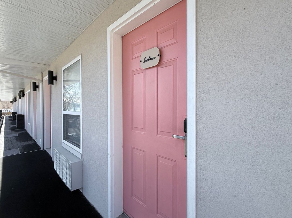 A pink motel-style door with a small sign that reads 