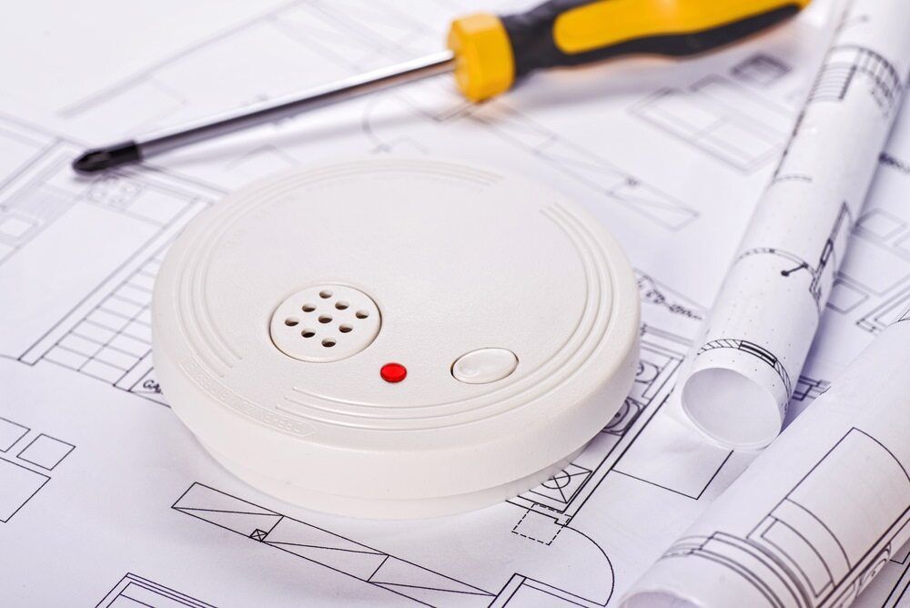 Smoke Detector, Screwdriver, and Rolled Blueprints on Architectural Plans — AJW Electrical & Solar in Roma, QLD
