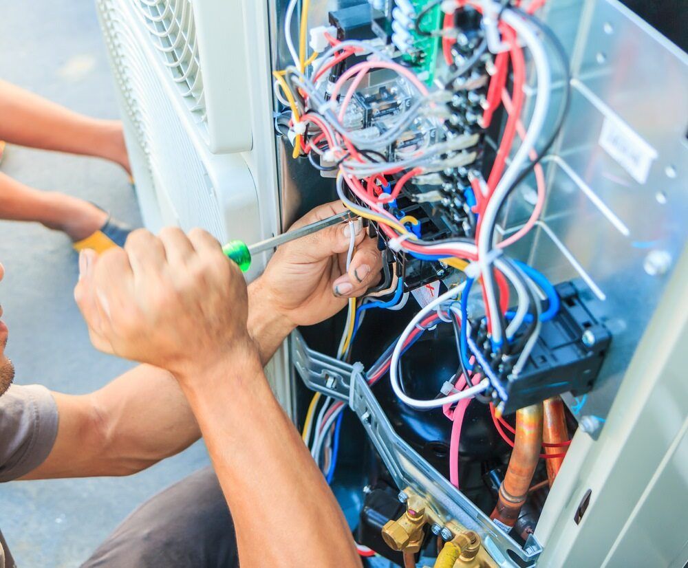 Person Working on an Air Conditioner With a Screwdriver and Wires — AJW Electrical & Solar in Roma, QLD

