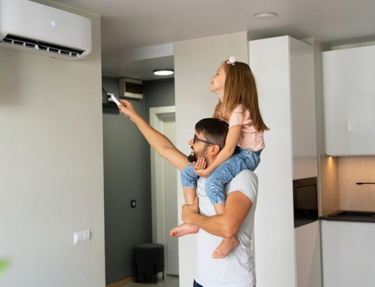 Man With a Girl on His Shoulders Adjusts Air Conditioning Unit — AJW Electrical & Solar in Roma, QLD