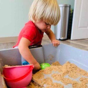 a little boy is playing in a sandbox with a bucket and shovel .