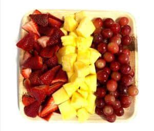a wooden tray filled with strawberries , pineapple , and grapes .