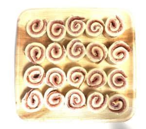 a wooden tray filled with swirls of food on a white background .