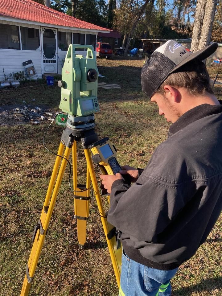 A man is standing in front of a tripod using a tablet.