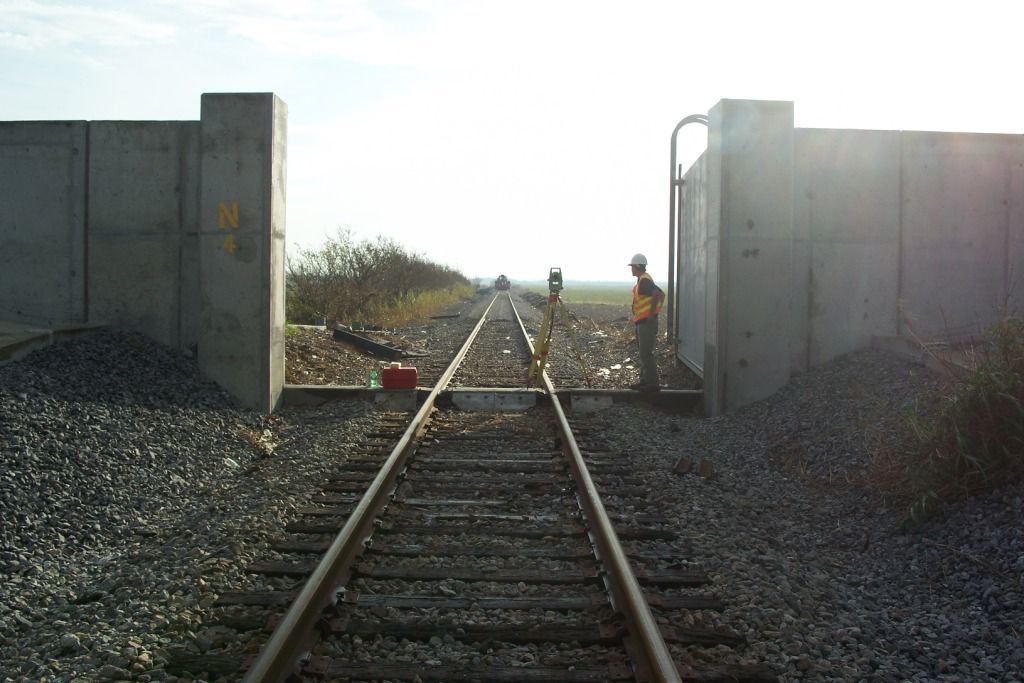 A man is standing on a train track next to a concrete wall.