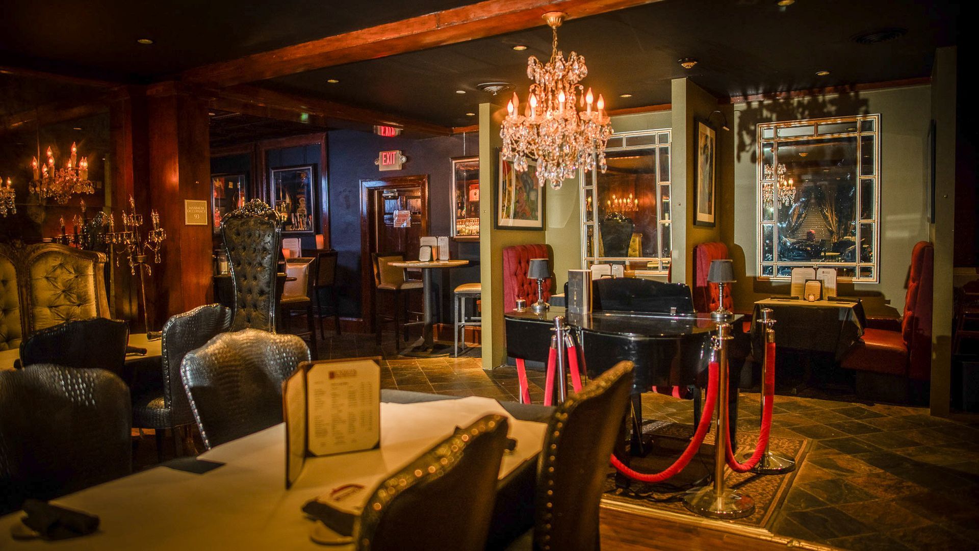 Elegant restaurant interior with dim lighting, chandeliers, tables, and velvet ropes.