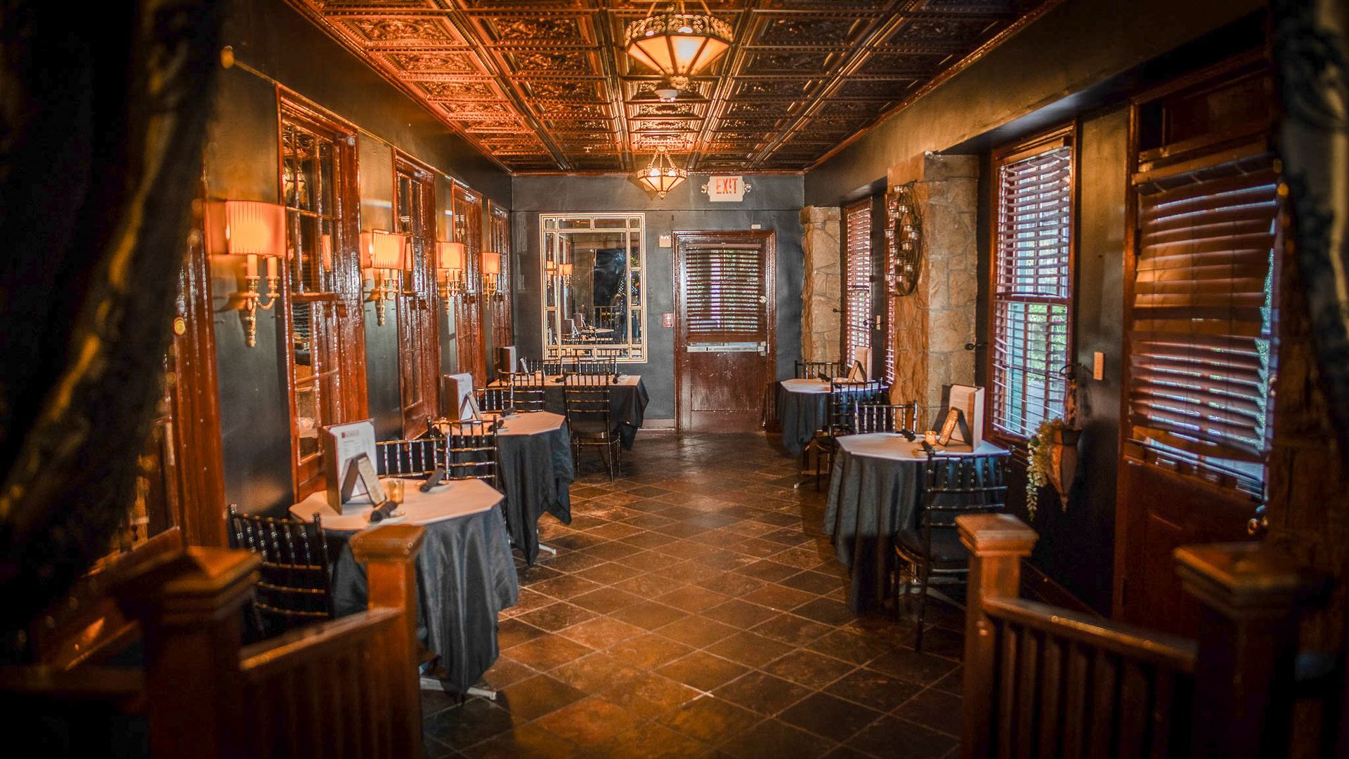 Dimly lit restaurant interior with tables, ornate ceiling, and decorative lights.