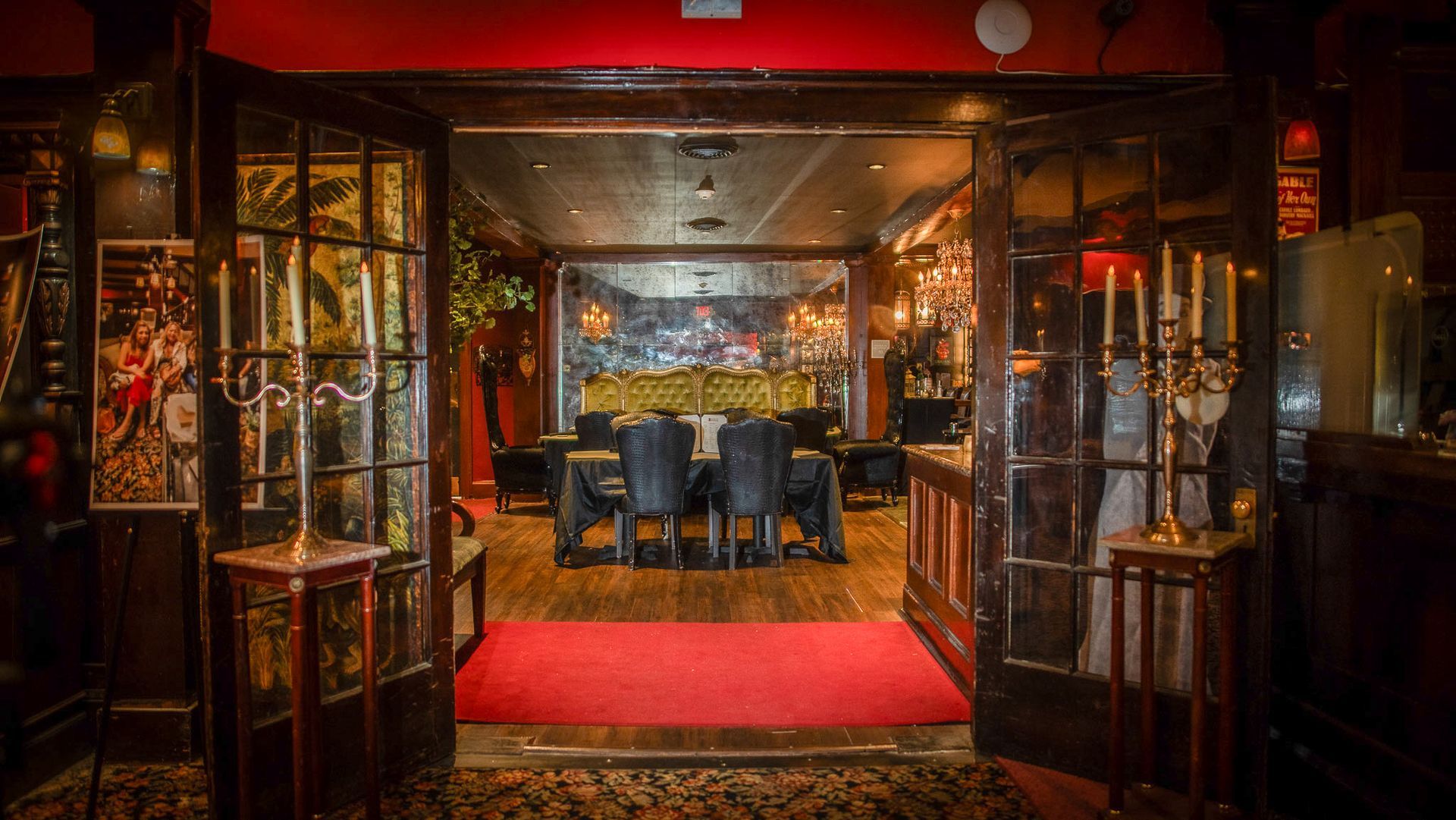 Open doorway to a dimly lit dining room. Red carpet, dark wood, ornate details. Table set for a group.