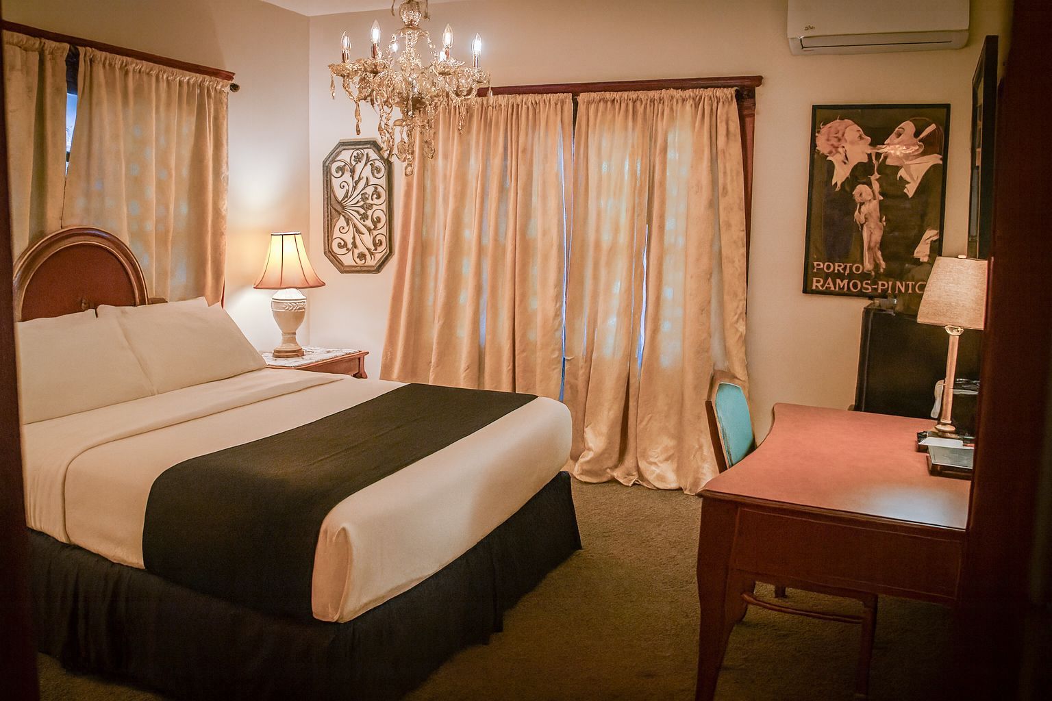 Bedroom with a bed, desk, chandelier, and a map hanging on the wall.