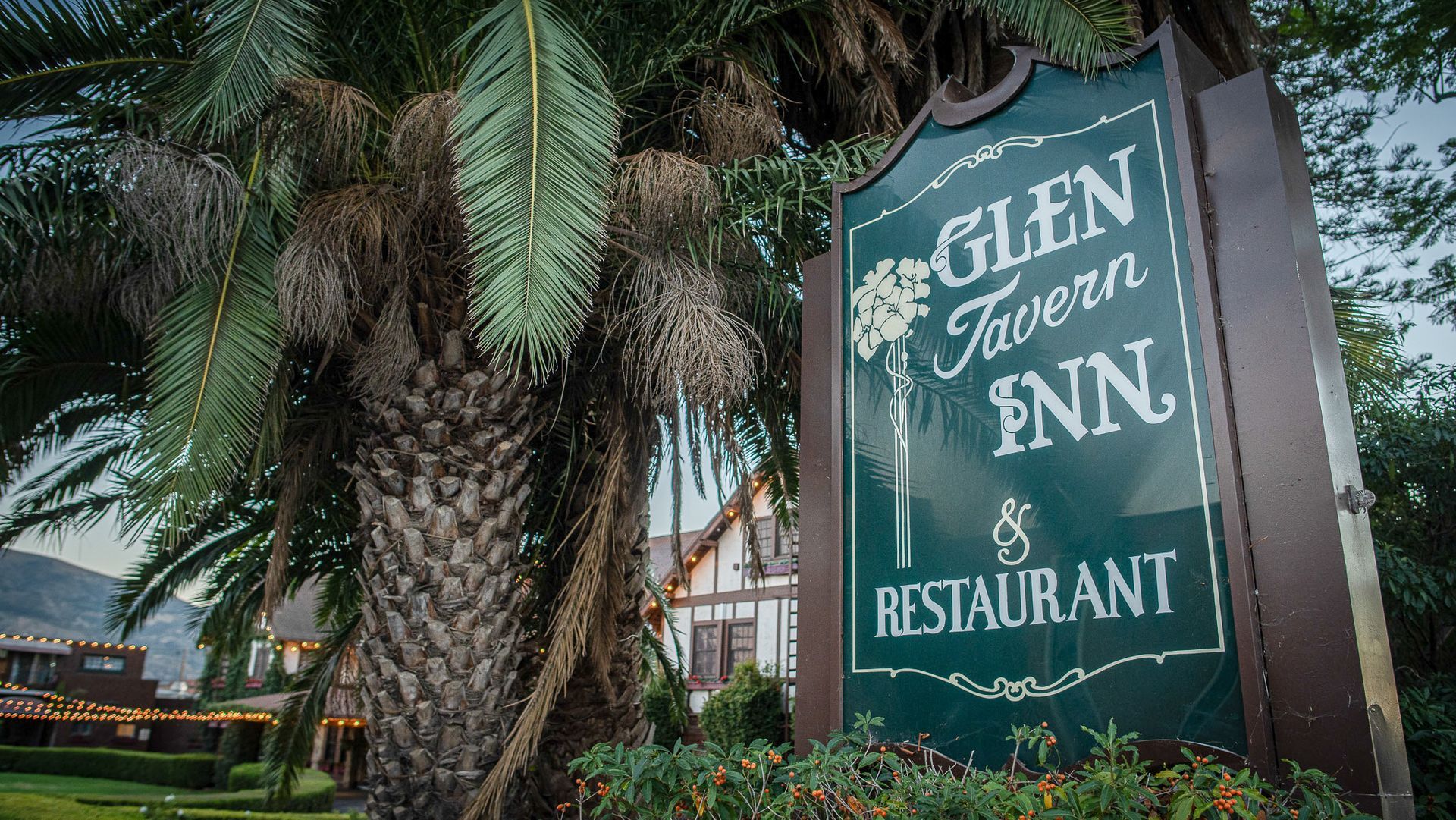 Sign for Glen Tavern Inn & Restaurant, palm tree in foreground, building in background.