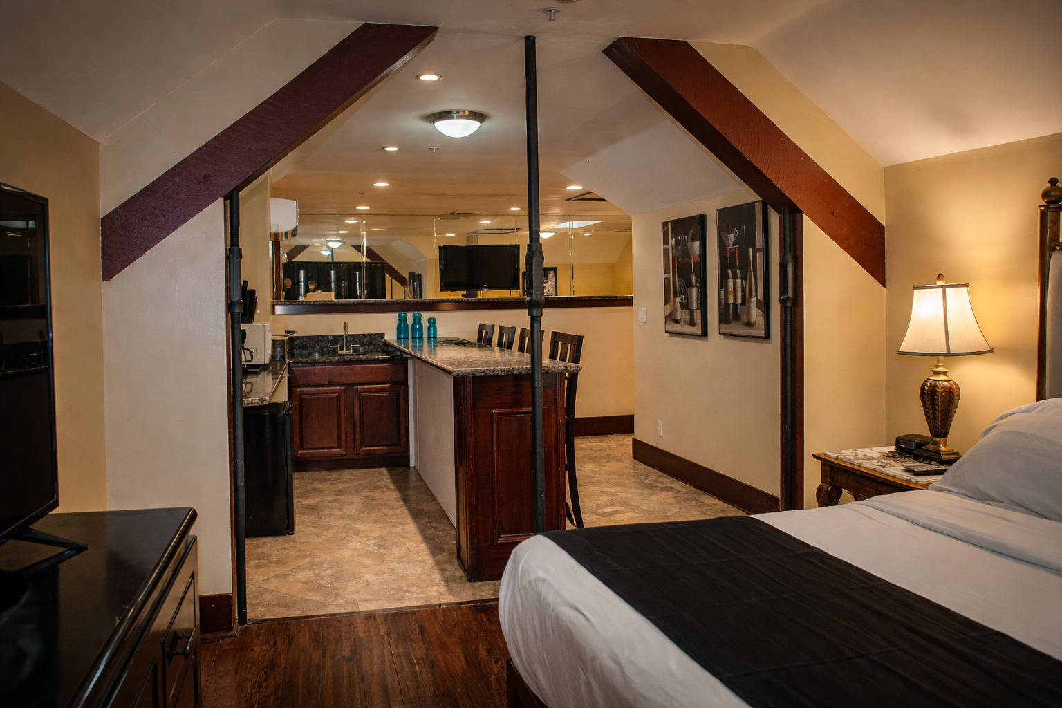 Hotel room with bed, mini-kitchen, and decorative beams.