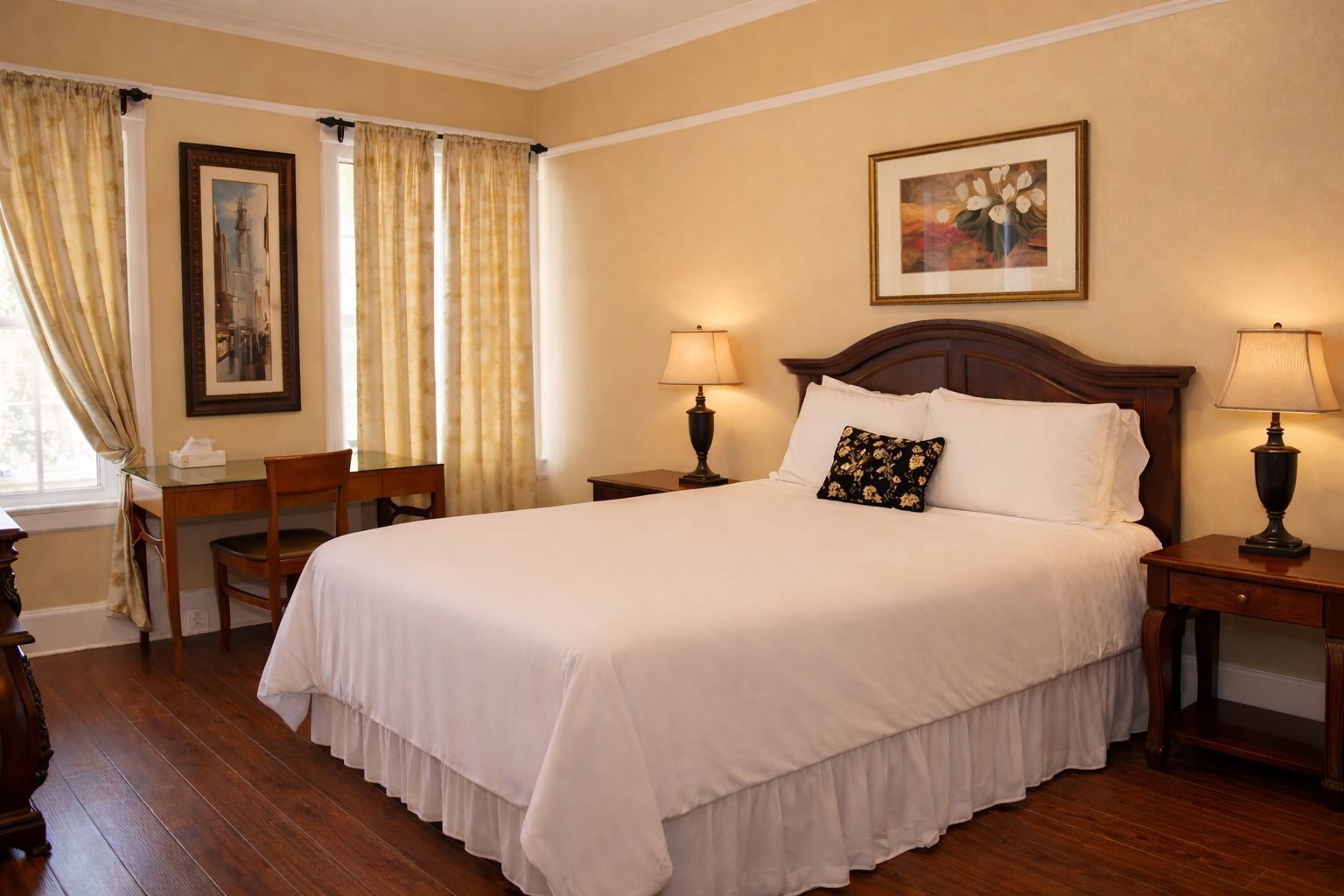 Bedroom with a bed, nightstands with lamps, artwork, and a window with curtains.