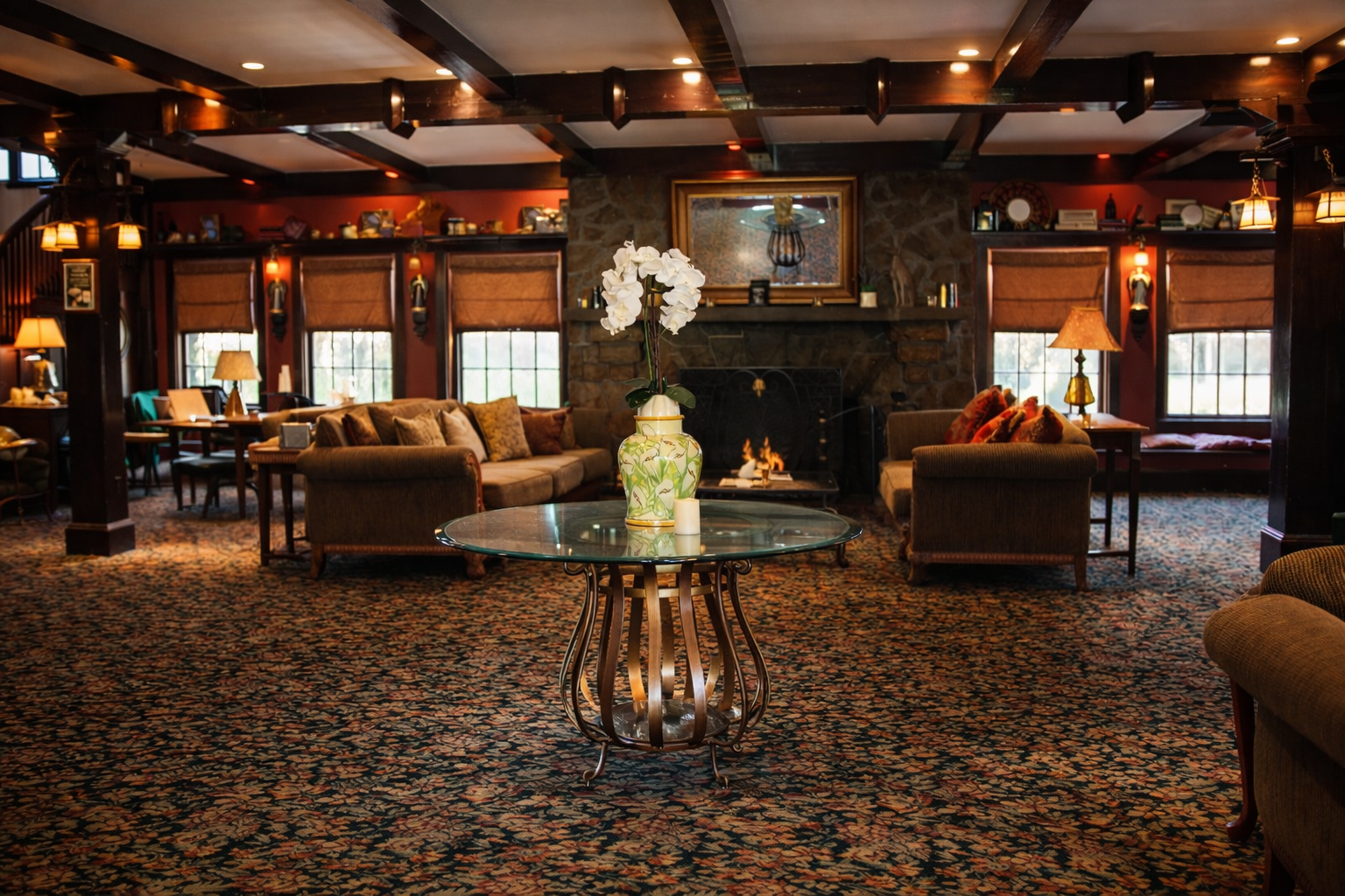 Cozy hotel lobby with fireplace, sofas, and a round glass-top table featuring an orchid.