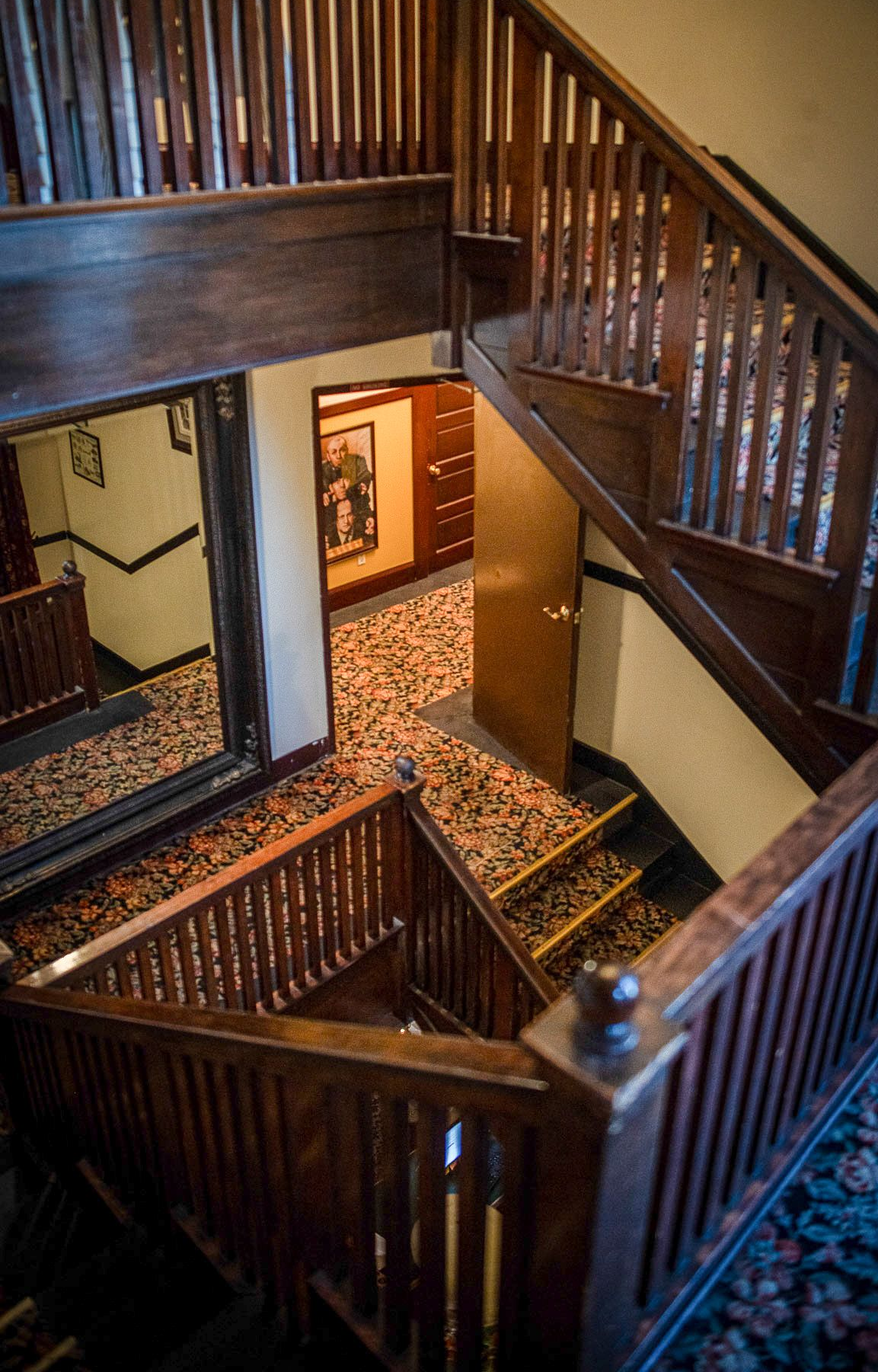Wooden staircase in a building, viewed from above. Staircases lead in different directions, opening to a hallway.