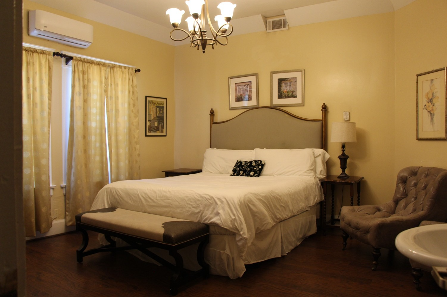 Bedroom with bed, bench, armchair, and antique decor.