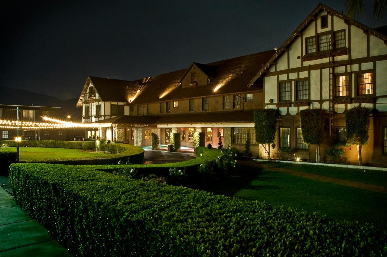 Night view of a Tudor-style hotel with exterior lights, well-manicured lawn, and dark sky.