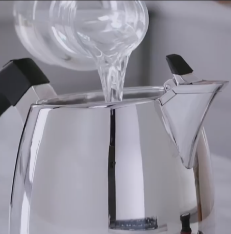 Agua vertiéndose en una cafetera expreso de plata.