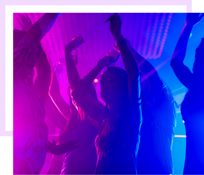 Des personnes dansent sous des lumières violettes et bleues dans une boîte de nuit.