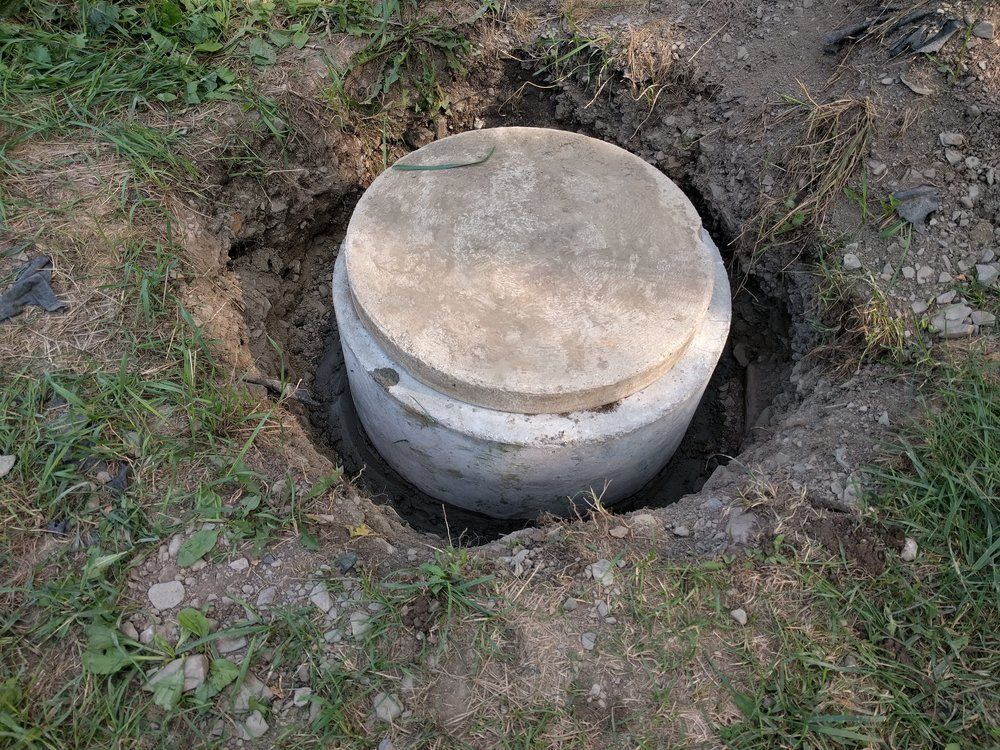 A concrete septic tank is sitting in a hole in the ground.