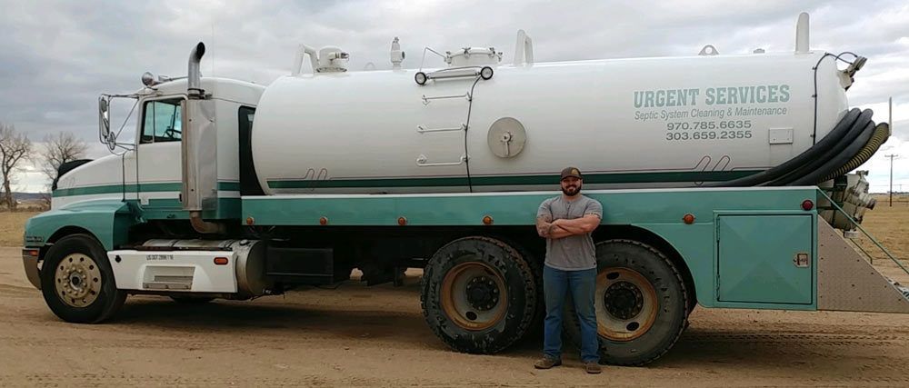 A man is standing in front of a vacuum truck.