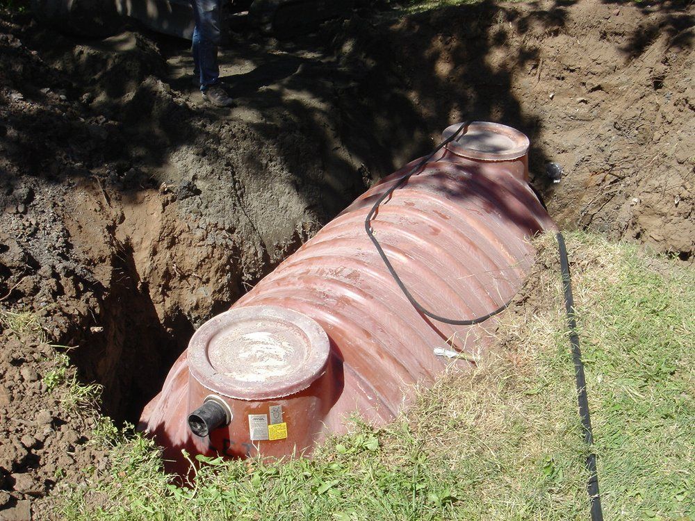 A septic tank is sitting in the dirt with a hose attached to it