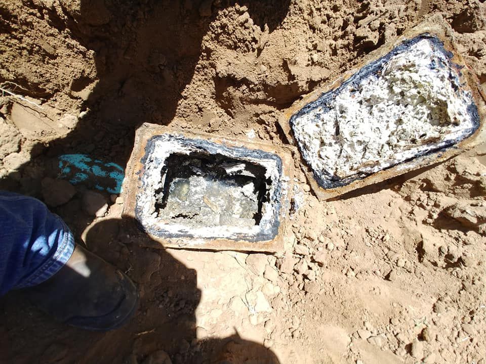 A person is standing next to a tray of food in the dirt.