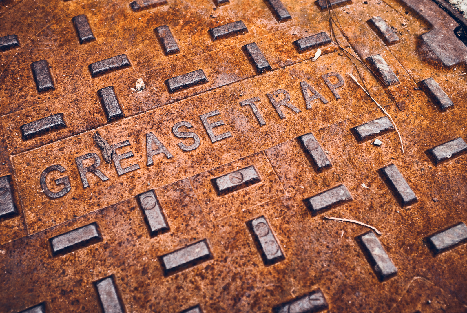 A rusty manhole cover with the words `` grease trap '' written on it.