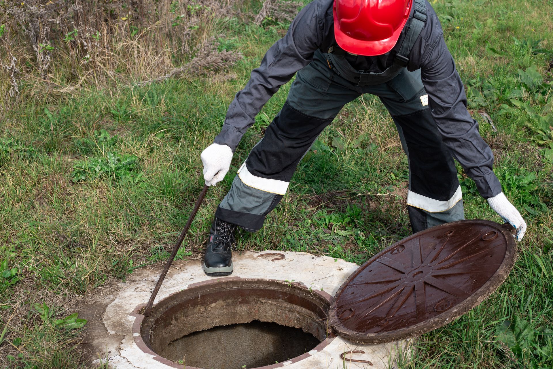 a man is opening a manhole cover with a stick .