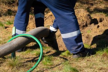 a person is standing next to a hose in the grass .