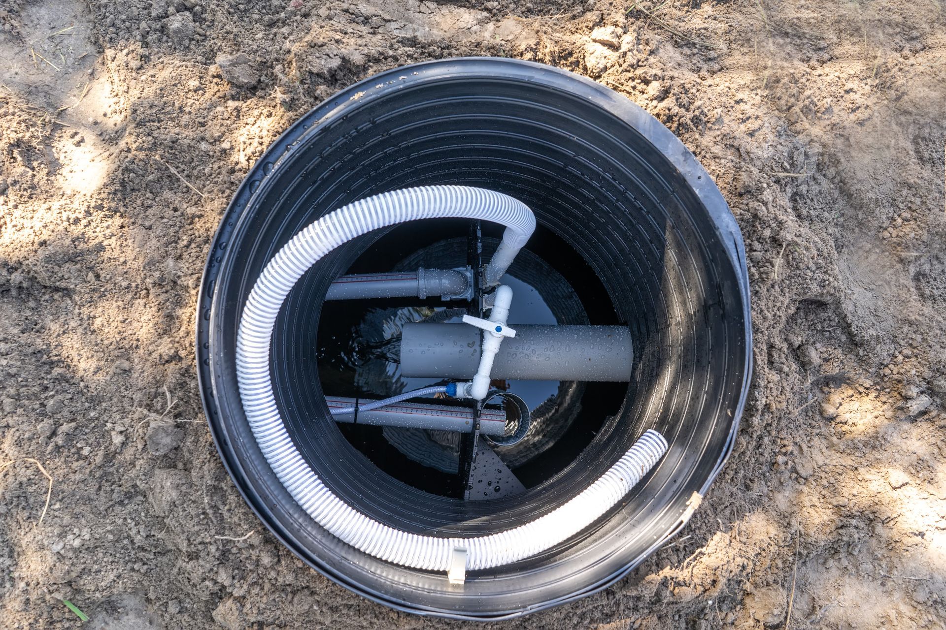 a black septic tank with a hose in it is sitting in the dirt