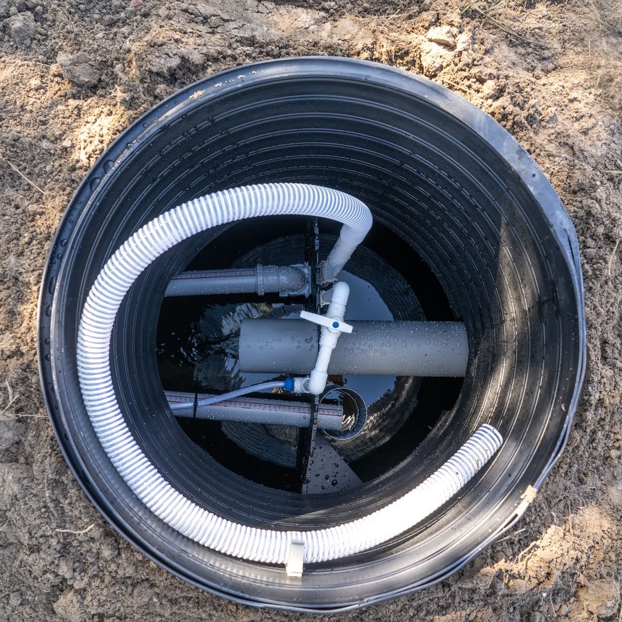 a hole in the ground with pipes coming out of it