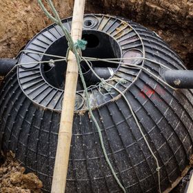 a septic tank is sitting in the dirt next to a wooden pole .