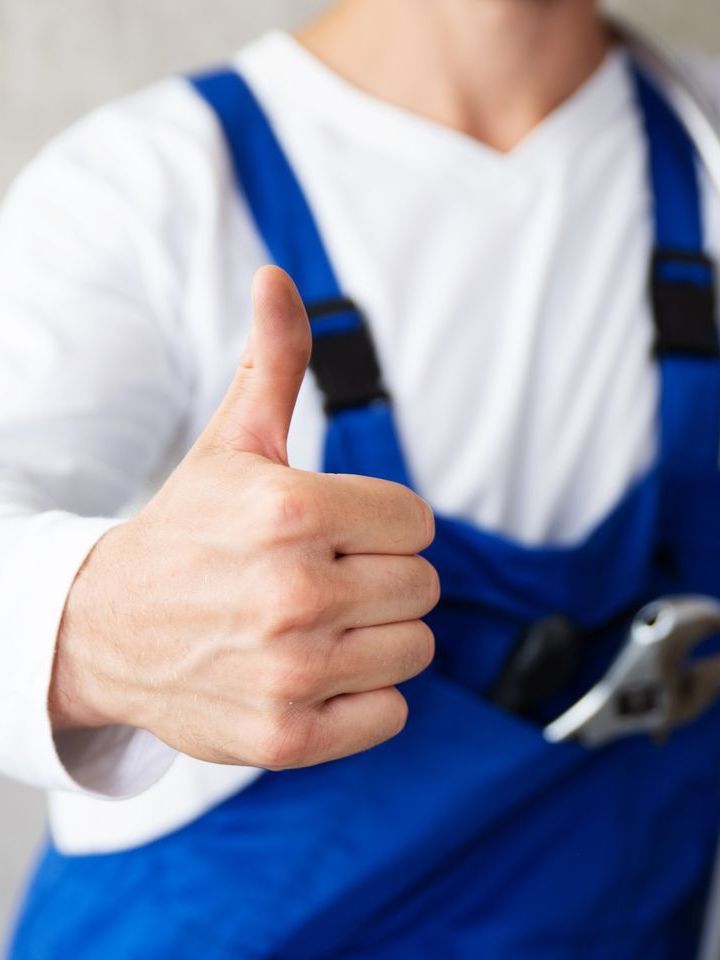 a man in blue overalls is giving a thumbs up