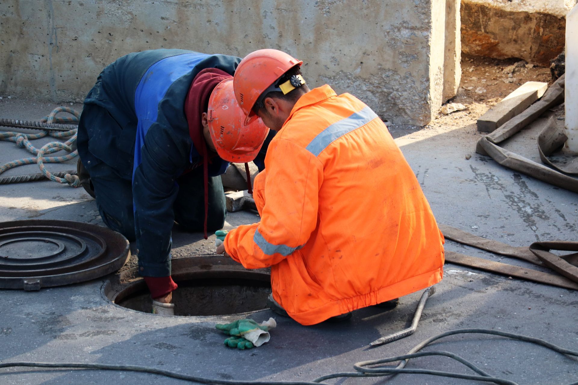 two construction workers are working on a manhole cover .