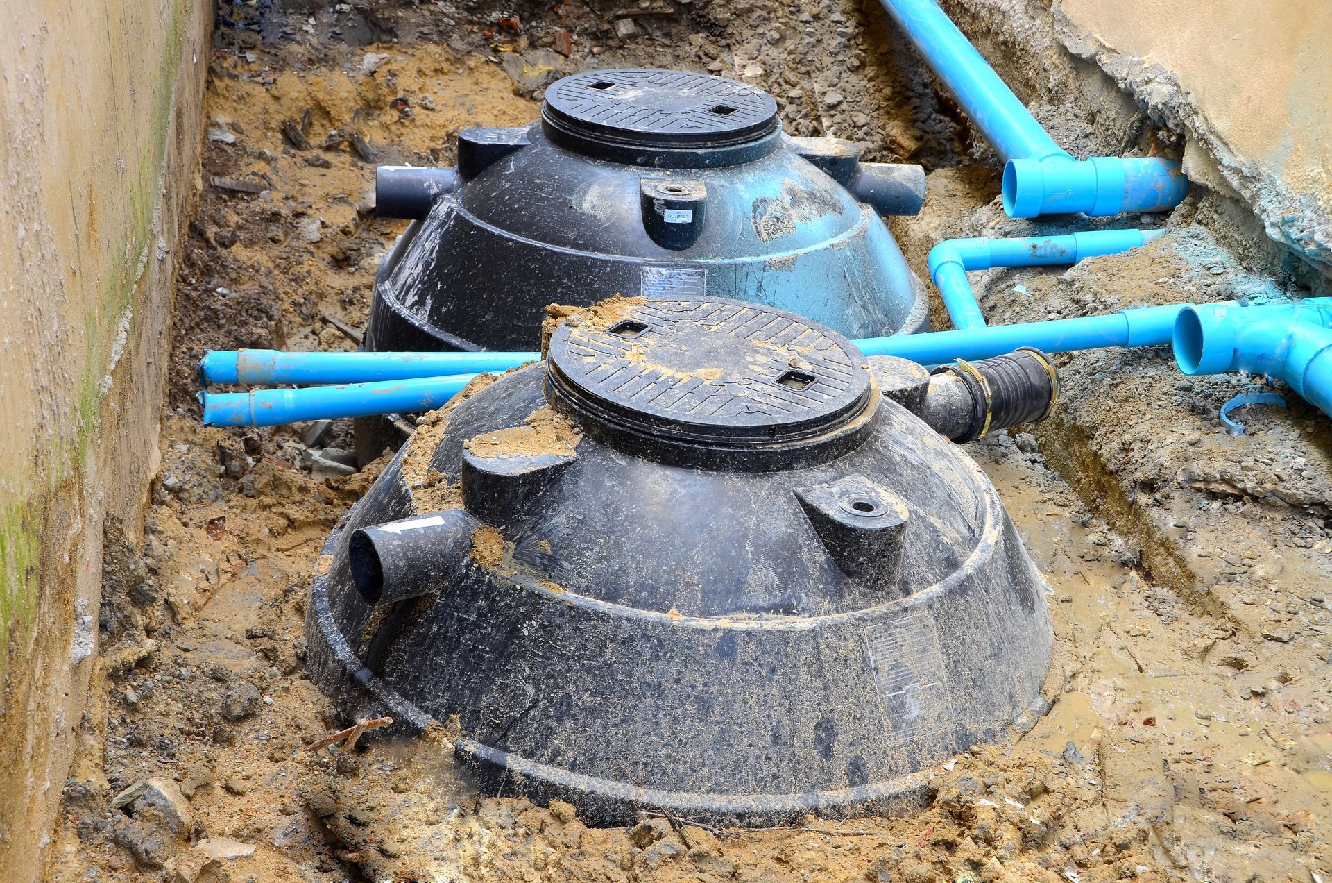 two septic tanks are sitting in the dirt next to each other .