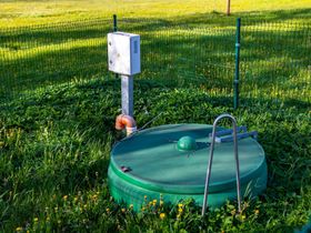 a green septic tank is sitting in the middle of a grassy field .