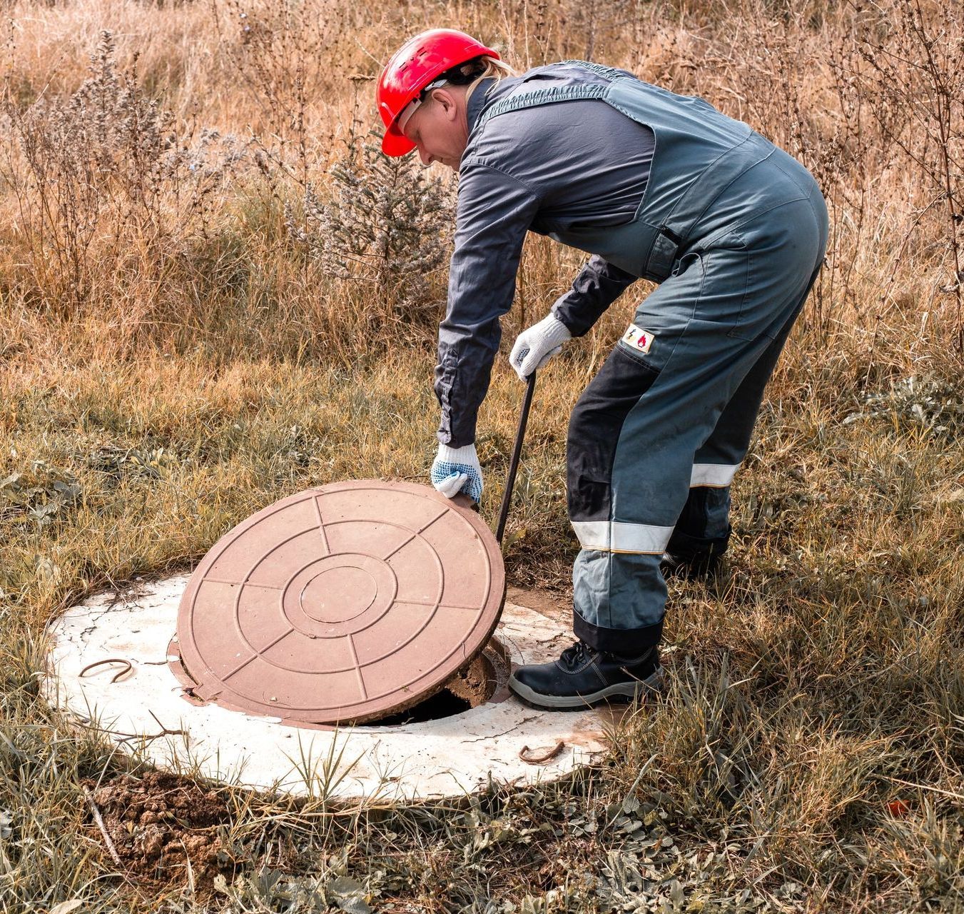 a man is opening a manhole cover in a field .