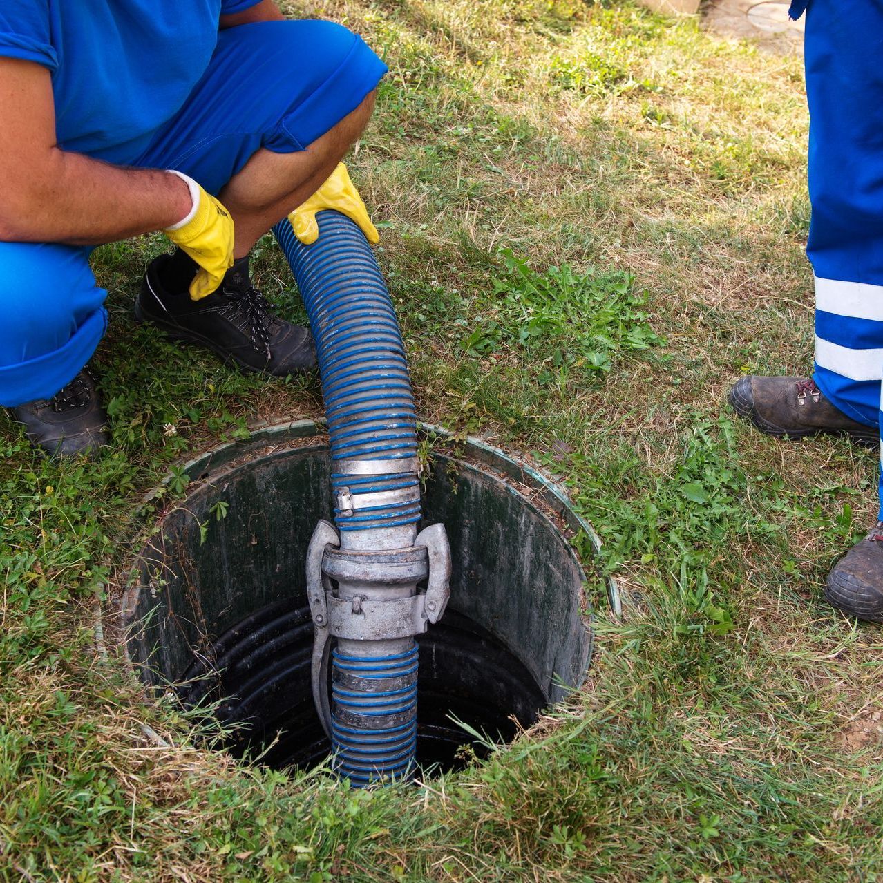 a man is kneeling in the grass with a hose coming out of a hole in the ground