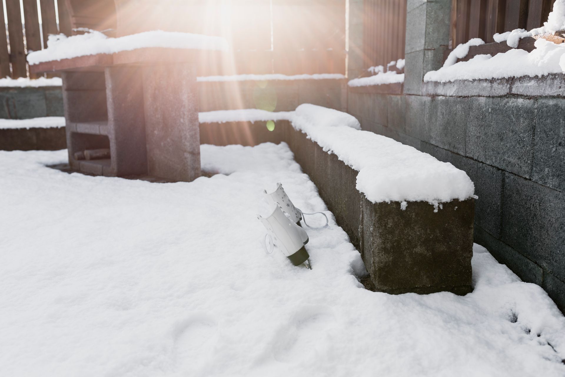 A snowy patio with a bench and a table covered in snow.