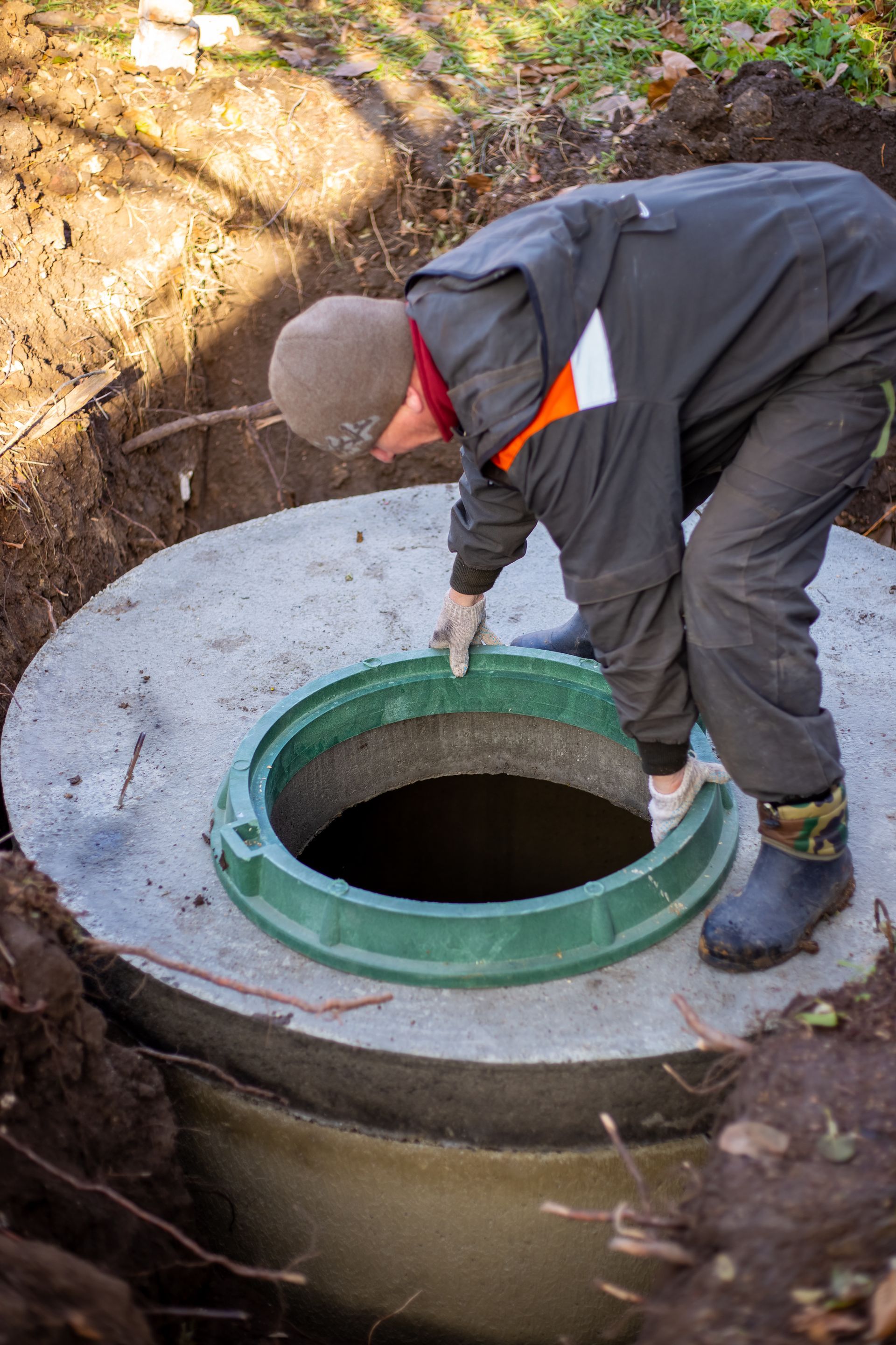 A man is working on a septic tank in the dirt.