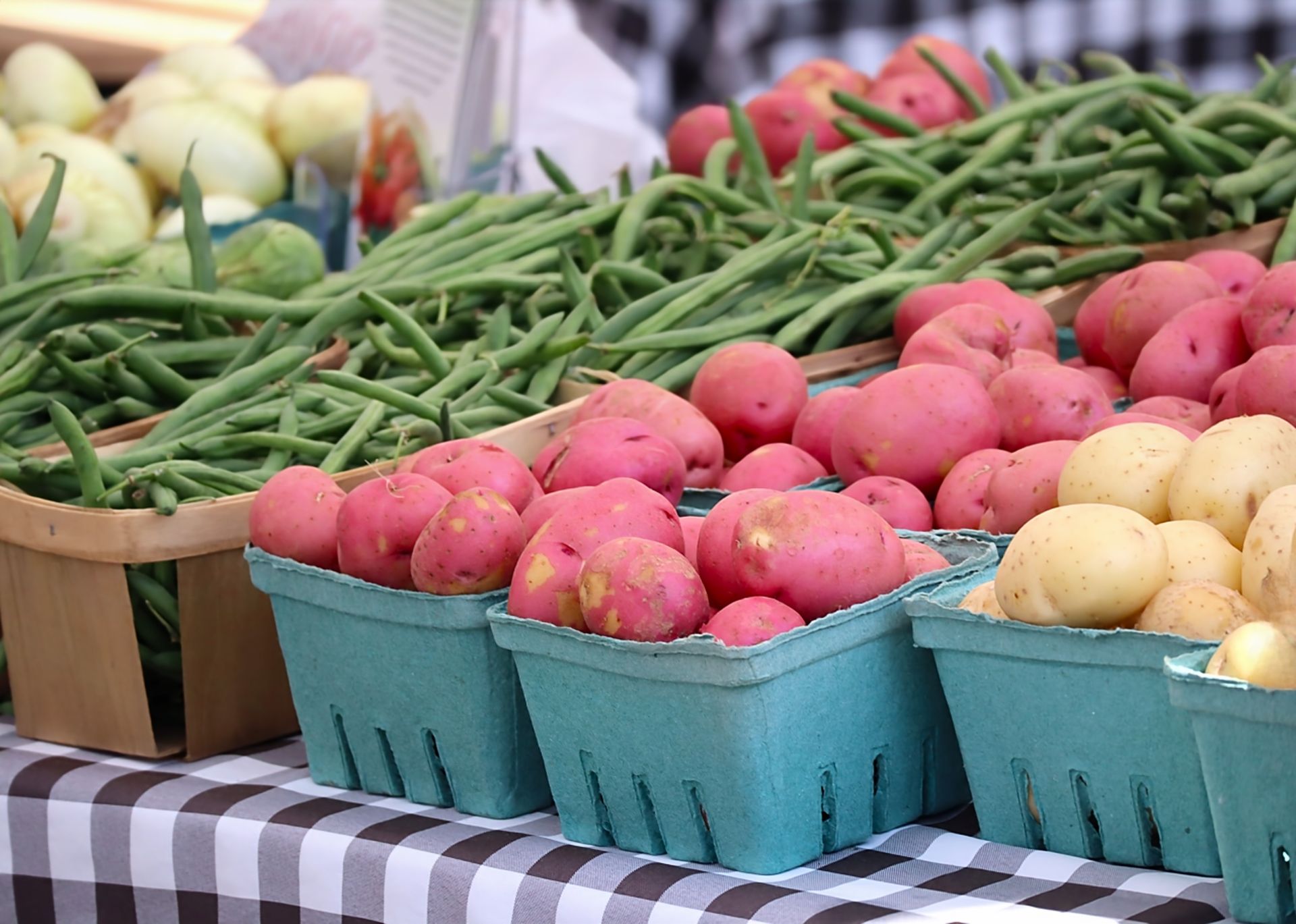 A table topped with baskets of potatoes and green beans.