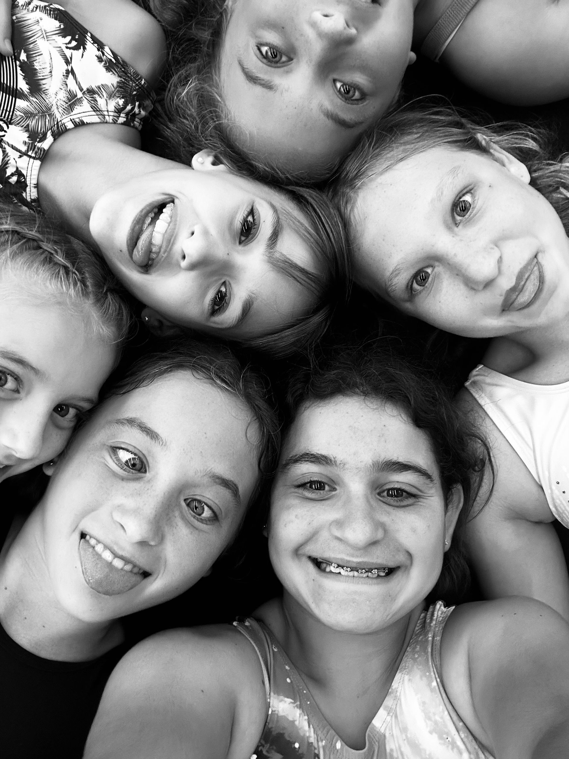 Smiling girls in a close circle, looking up.