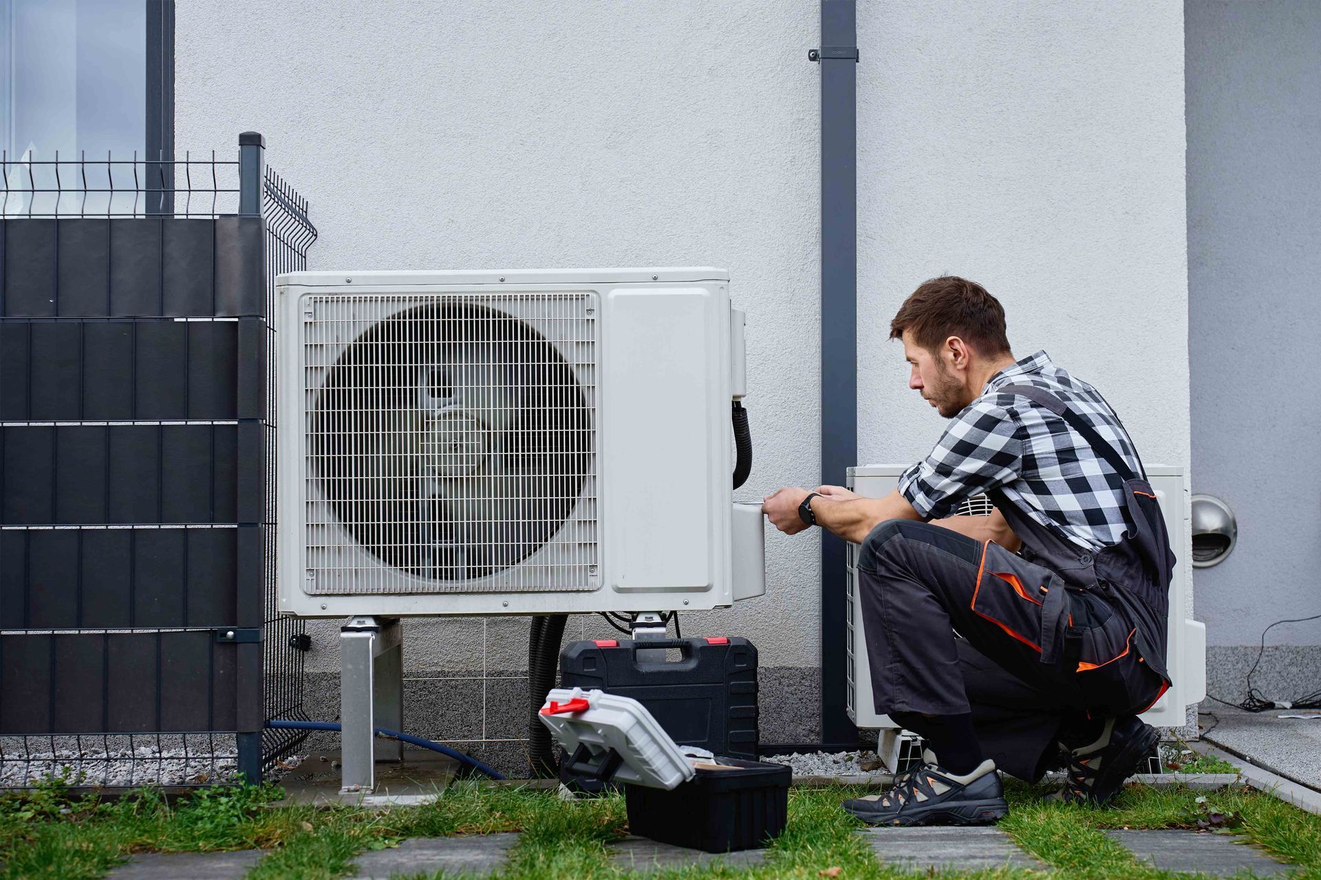 Residential HVAC contractor servicing an outdoor air conditioning unit at home.