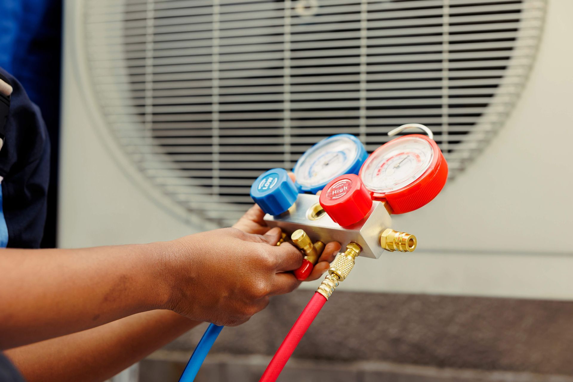 Close-up of an HVAC contractor checking refrigerant pressure with manifold gauges.