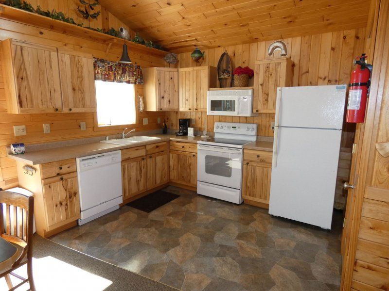 Wood-paneled kitchen with white appliances, wood cabinets, and a patterned floor
