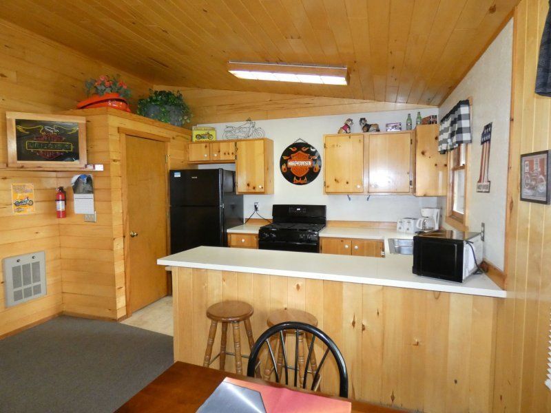 Cozy wood-paneled kitchen with black appliances, white counters, and a small dining counter