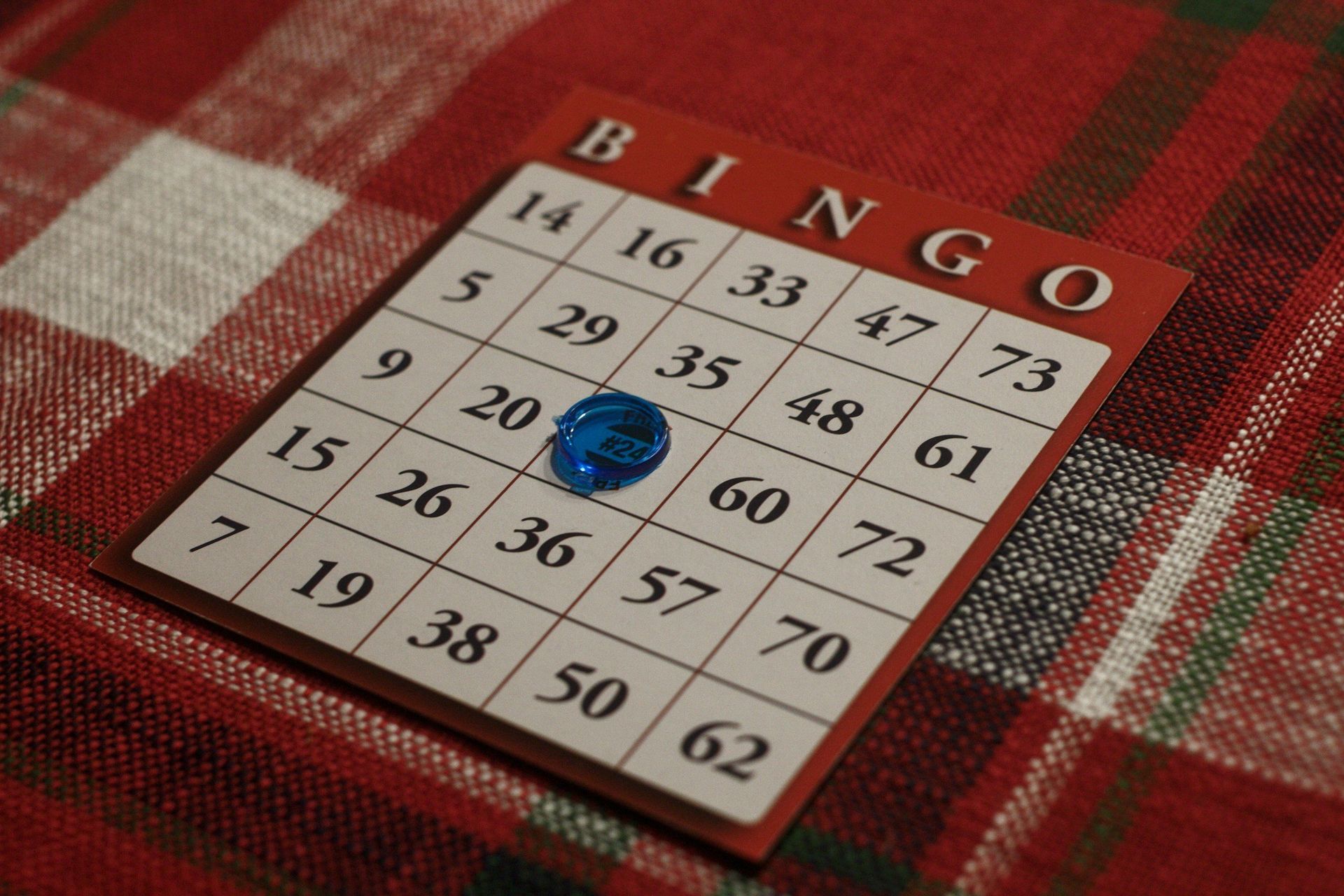 Bingo card on a red tablecloth, with a blue marker highlighting a number in the center